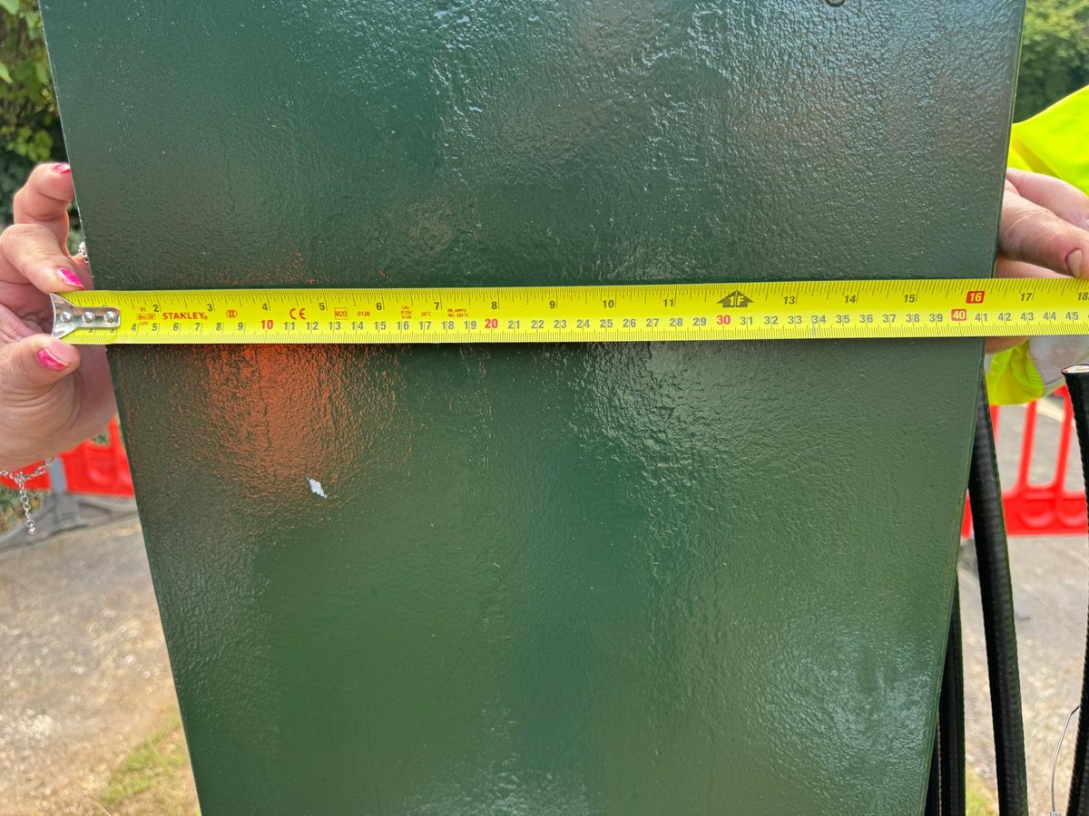 A steel tape held flat across one face of the green base enclosure of the new mast, reading about 39 centimetres from edge to edge